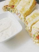 Sliced shawarma wraps arranged on a plate, showing colorful filling with a garnish of herbs.