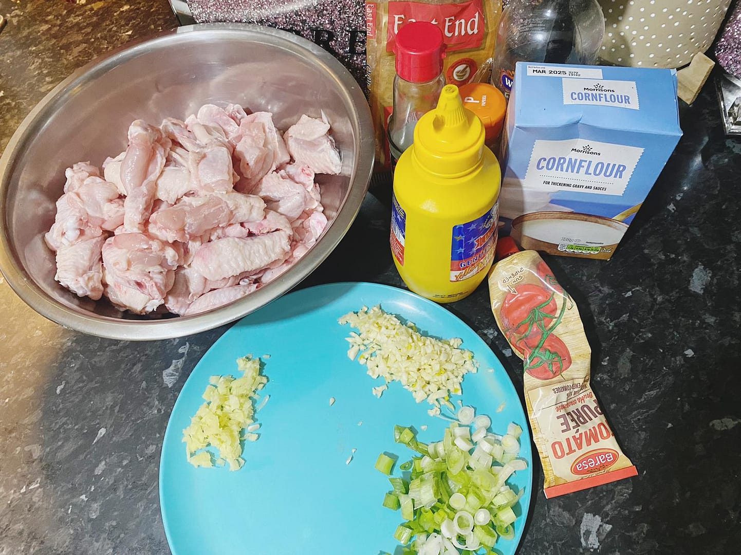 Fresh chicken wings with chopped garlic, ginger, and spring onions, ready for seasoning with sauces and spices.