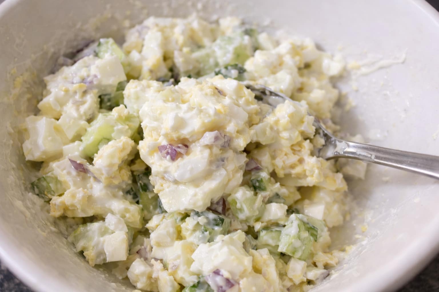 Creamy egg salad mixture with cucumber and red onion prepared for avocado egg toast