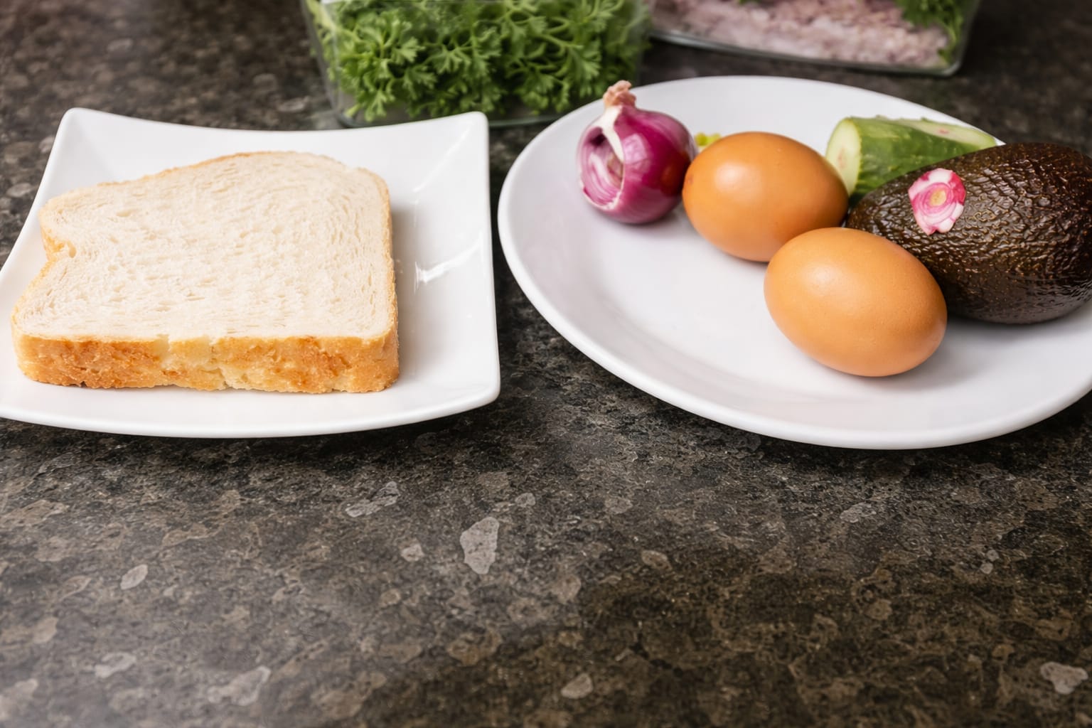 Avocado toast ingredients including sliced bread, eggs, red onion, and ripe avocado on plates ready for preparation