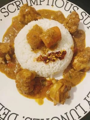 Chicken curry wings served in a bowl with rice and garnish