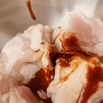 Mixing BBQ marinade with soy sauce, vinegar, and honey in a glass bowl