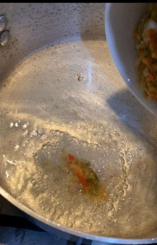 A blender filled with onion, spring onion, and red paprika, ready to be blended into a paste.