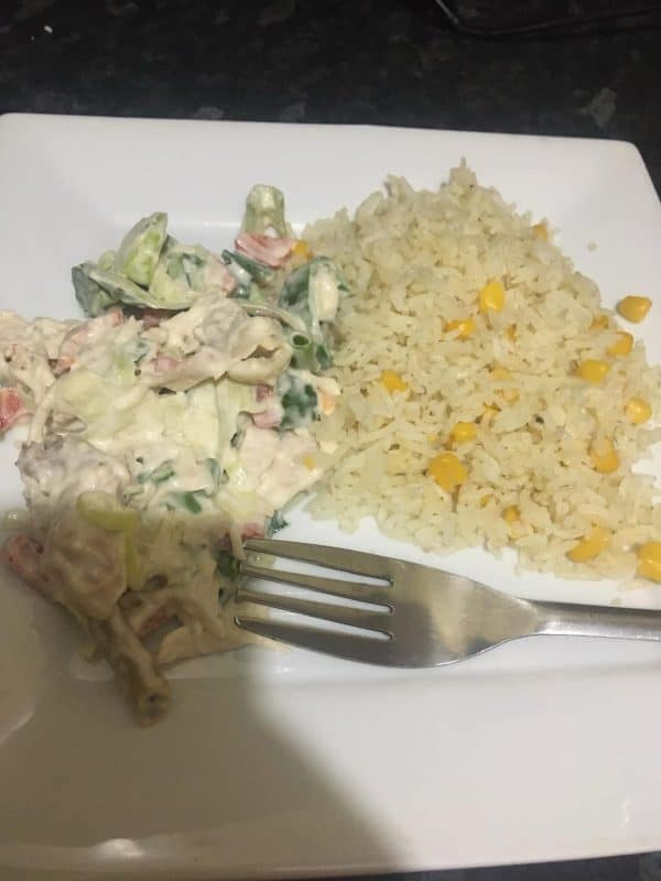 Plate of creamy chicken salad served with sweet corn rice on a white square dish
