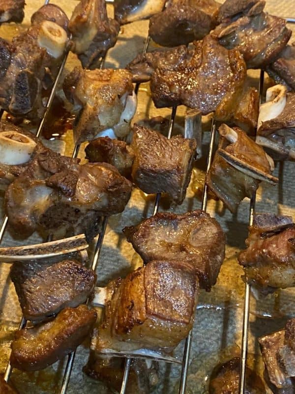 Golden-brown meat roasting on a baking rack in the oven.