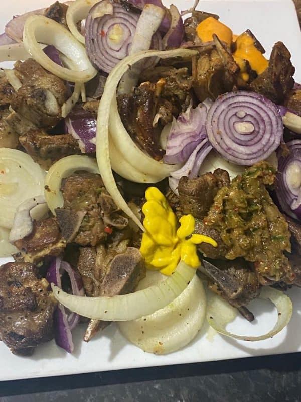 Oven-baked seasoned meat topped with fresh onion slices and lemon zest.