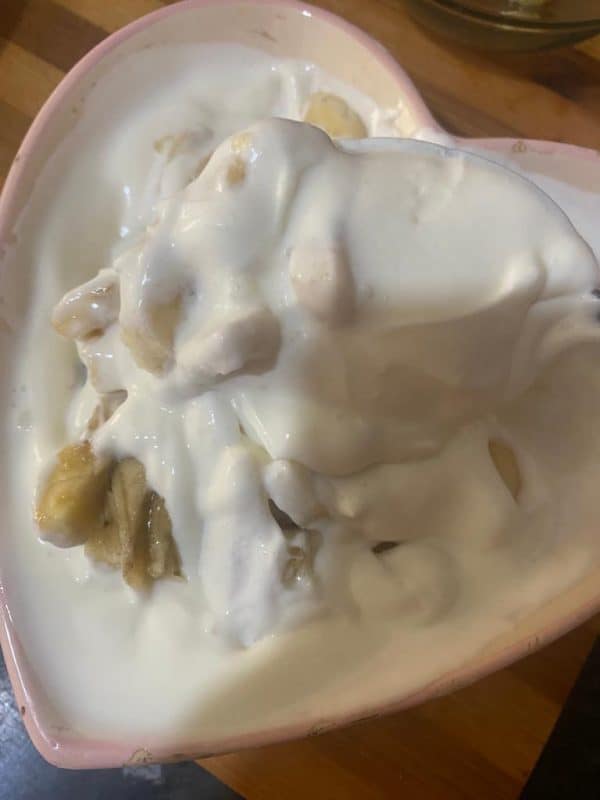 A warm bowl of Chura Gerteh topped with yogurt, banana slices, and fresh fruit – a comforting Gambian breakfast.