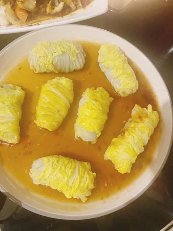 Steamed cabbage wraps served in a soy–oyster glaze on a plate