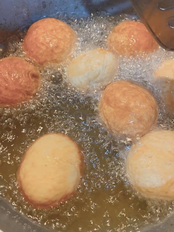 Cinnamon roll bites frying in hot oil until golden brown.