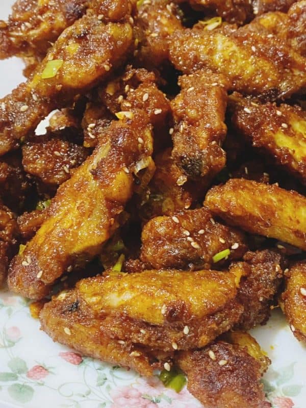 Crispy honey and sour chicken wings coated in sauce and sprinkled with sesame seeds.