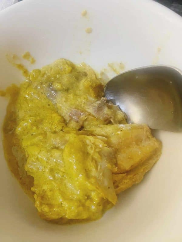 Mackerel being mashed in a mixing bowl with a fork to create a creamy fish spread