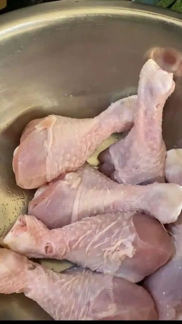 Raw chicken drumsticks lightly seasoned with salt, arranged in a bowl, ready for cooking.