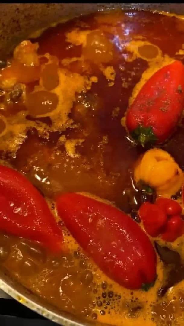 Golden chicken drumsticks simmering in red nokos-tomato sauce with vegetables.