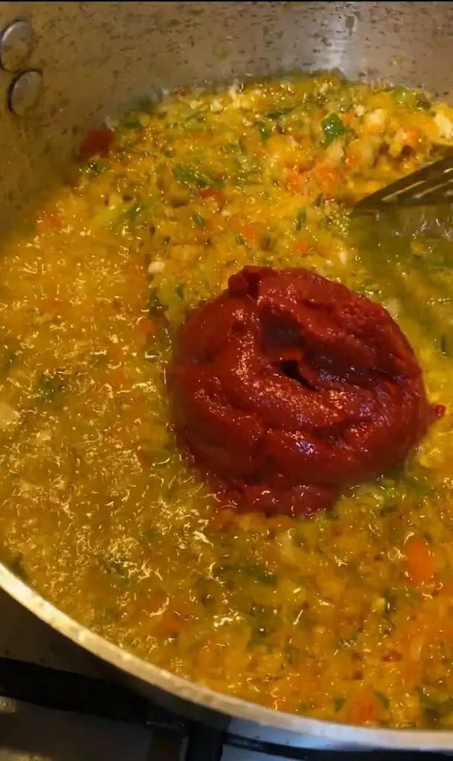 Tomato paste being sautéed in a pot, deepening in color.