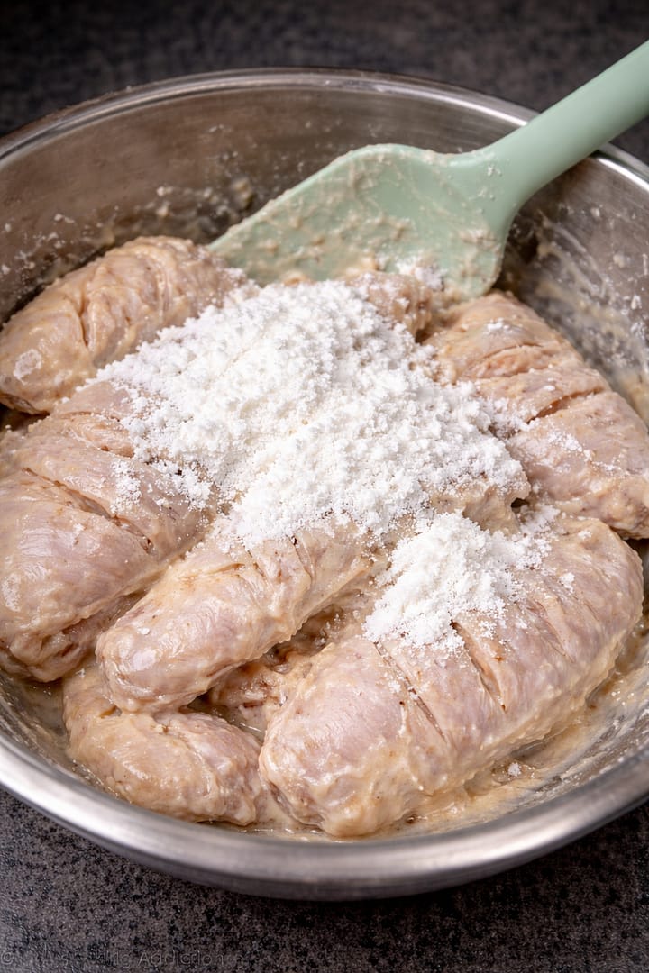 Chicken wings coated in marinade with cornflour added on top before mixing