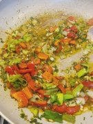 Colorful chopped vegetables sautéing in hot oil inside a pan.