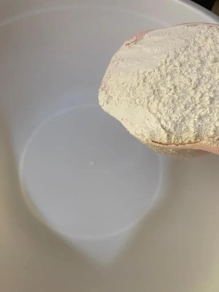 Adding flour to a large mixing bowl for homemade spring roll batter