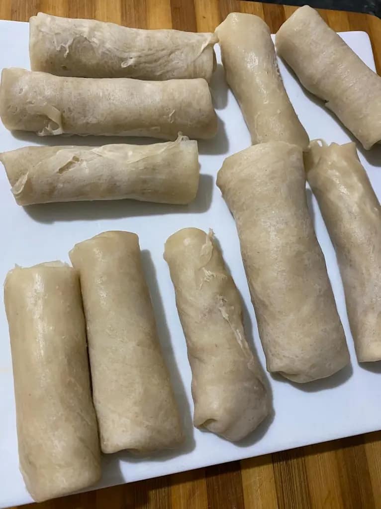 Uncooked spring rolls neatly arranged on a white tray