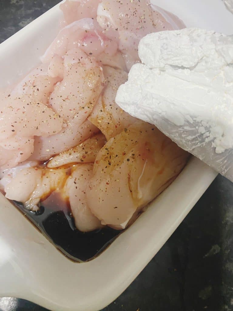 Chicken pieces marinating in soy sauce, rice vinegar, and cornflour mixture.