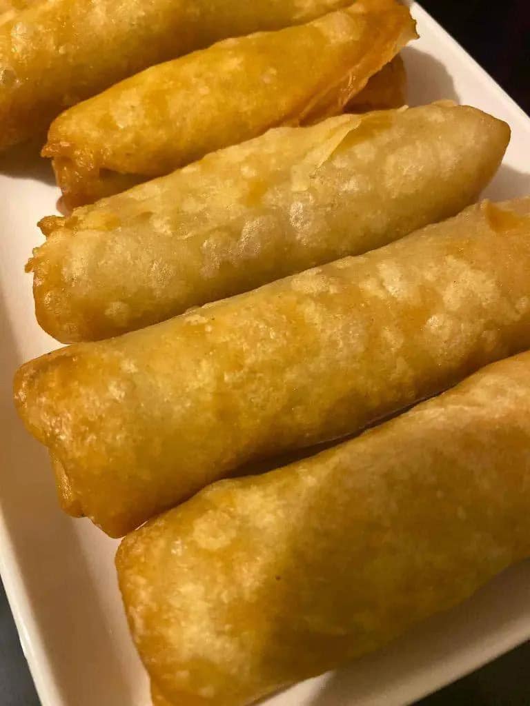 Golden fried spring rolls resting on paper towels