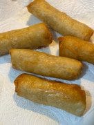 Golden fried spring rolls resting on paper towels