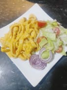 Creamy chicken pasta served on a white plate with a fresh side salad and sliced red onions.
