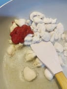 Tomato paste added to diced chicken in a pan, ready to be cooked