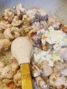 Golden chicken wings with sautéed onions and garlic in a pan