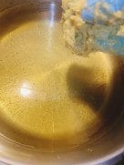 Prawn pakora batter being dropped into hot oil in a pan