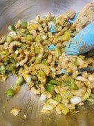 A hand mixing the pakora ingredients into a cohesive blend.