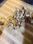 Cooked chicken being sliced into thin strips on a wooden board, showing juicy texture inside.