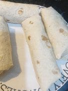 Tortilla laid flat with chicken, sautéed vegetables, and pickles layered in the center.