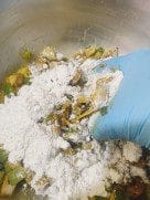 A spoon scooping up the thick pakora batter from the bowl